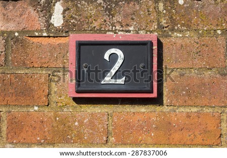 House number two sign on a red brick wall