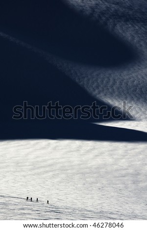People skiing on glacier in La Grave with strong shadows painting in the field of snow