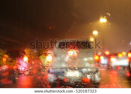 Blurry image of inside cars with bokeh lights with traffic jam and raining on night time for background usage.