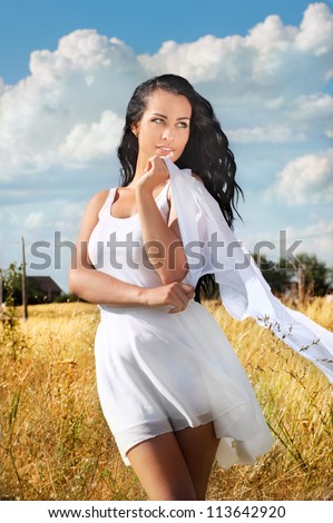 Beautiful young woman in white dress on rural background