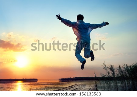 Silhouette of man jumping in sea sunset