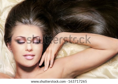 Portrait of charming happy woman with beautiful long hair on light yellow glossy cloth