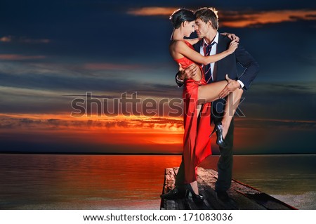 Beautiful romantic couple in tango pose against sunset background Beautiful romantic couple in tango pose against sunset background