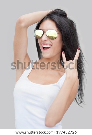 Portrait of joyful young woman in mirrored sunglasses showing rocker gesture