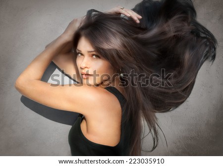 Portrait of beautiful young woman with long hair on gray background