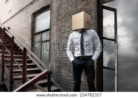 Man with carton box on head on brick wall background