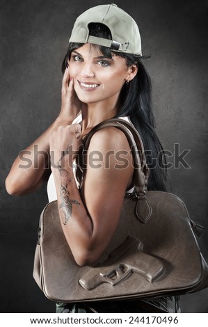 Portrait of beautiful smiling woman holding leather bag with image of pistol