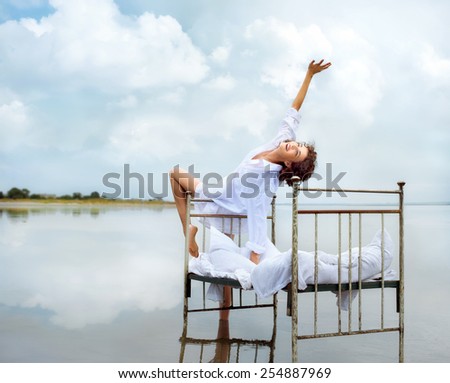 Happy young woman in water on beach. She is enjoying morning nature near retro bed in water, during vacation outdoors.