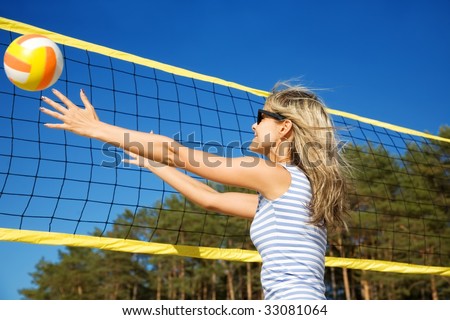 The happy cheerful girl playing with a ball at a volleyball net in motion
