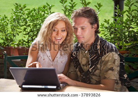 Happy cute couple with a laptop on a background of green foliage