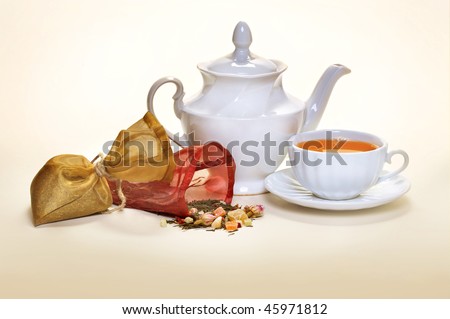 Pouches with tea for tea leaves and a white teacup and a teakettle  with a saucer