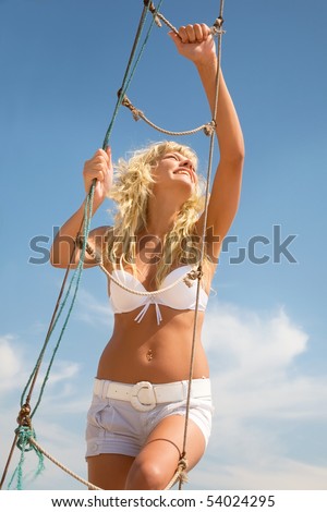 Picture of beautiful happy girl  on a rope ladder on sky background