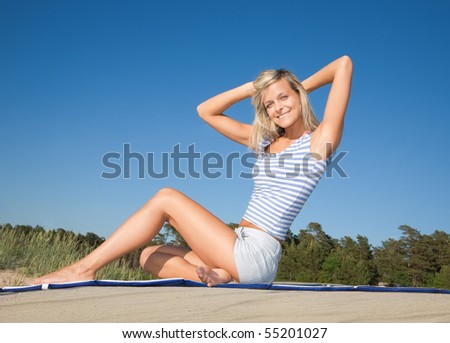 Beautiful young girl relaxing on sea beach against blue sky