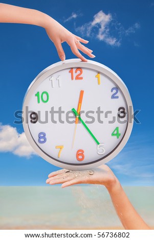 Cheerful picture of female hands holding color watch and sand handful on sky background