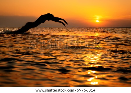 Seascape with  swimmer silhouette and gold water on sunset background
