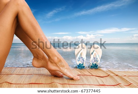 Picture of beautiful female legs and sandshoes on sea background