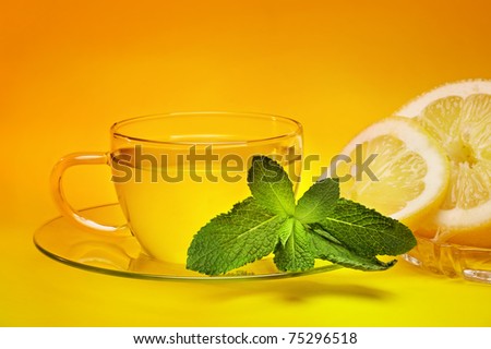 Cup of tea with spearmint and lemon isolated on orange background