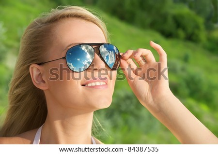 Portrait of beautiful happy woman in mirrored sunglasses against green background