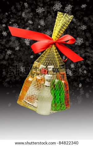 Christmas gift. Small packing of colorful bottles with alcohol on black and white background.