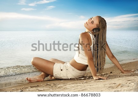 Attractive woman listening to music on beach
