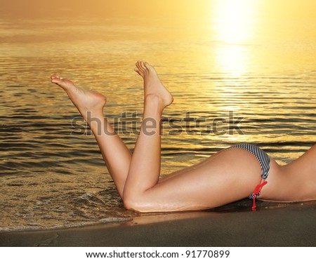 Beautiful female legs against of sea sunset