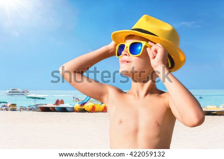 Happy child in yellow sunglasses on beach. Summer vacation concept
