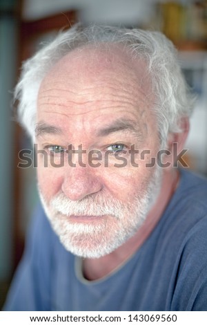 Neutral expression, caucasian man with white beard.