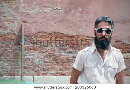 Portrait of a hipster with white glasses, wall on the background
