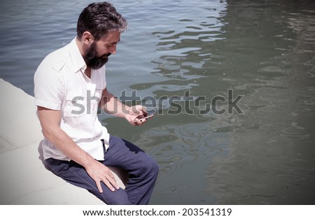 Man with his smart phone, water on the background