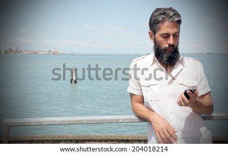 Man checks his smart phone, water on the background