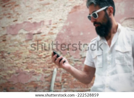 Hipster checks his agenda on the smart phone. Intentionally blurred background.