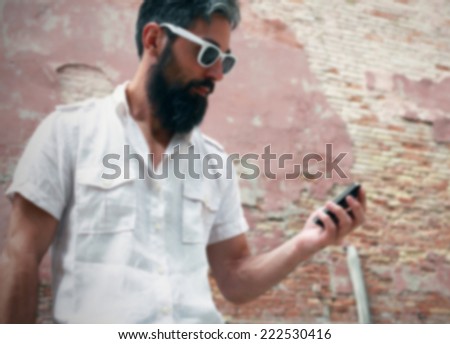 Hipster checks his agenda on the smart phone. Intentionally blurred background.