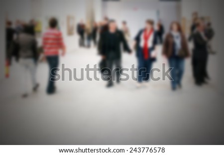 People visit an art gallery, generic background. Intentionally blurred post production.