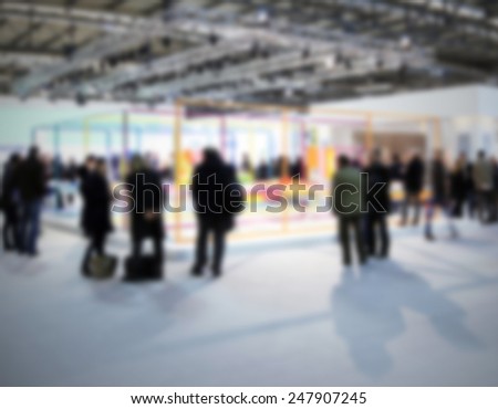 People visit a trade show. Intentionally blurred background.