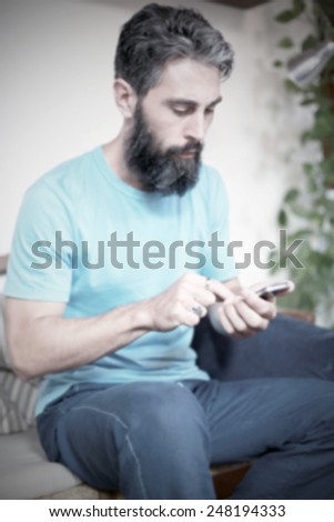 Hipster and his smart phone. Intentionally blurred post production.