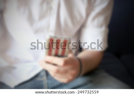 Smart phone with a US flag cover in man\'s hand. Intentionally blurred editing post production background.