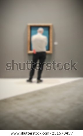 Man at art gallery, generic background. People, location and works not recognizable. Intentionally blurred editing post production.
