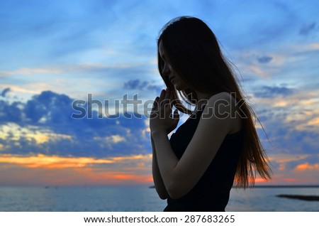 girl folded her hands in prayer at sunset
