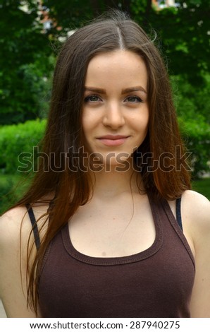 beautiful slender fair-skinned girl smiling. It stands on a green background, in nature. Fresh air. Summer.