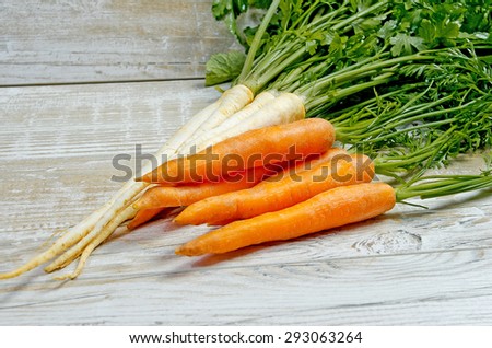Young spring vegetables on wooden background. Carrots, parsley - fresh harvest from the garden
