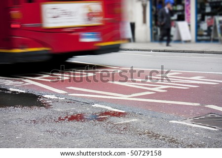Bus lane in London with red bus crossing over the sign