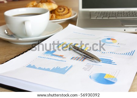 Business breakfast scene with graph, croissant, coffee and laptop
