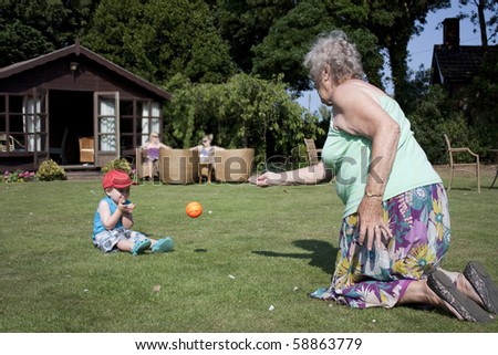 Elderly gran and little boy play catch in the garden