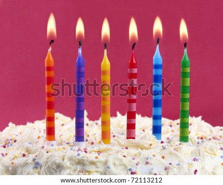 birthday cake with 6 coloured candles on a red background