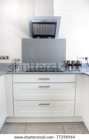 modern kitchen with white units and extrator fan and hob
