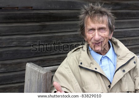 elderly man sat on a bench outside a allotment shed