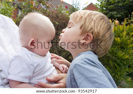 blonde toddler age 4 kissing 6 month old baby, brother and sister