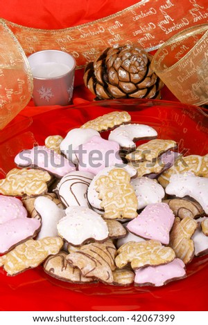 Assorted Christmas gingerbread cookies on a red plate and Christmas decorations over a red background