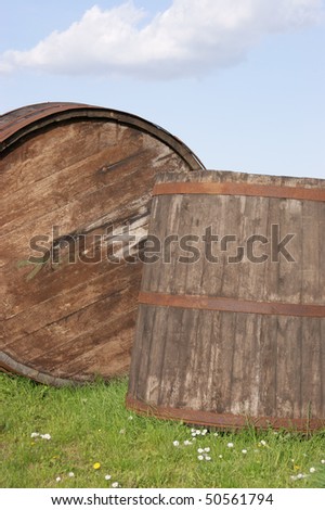 A tub and a barrel in a meadow against blue sky.