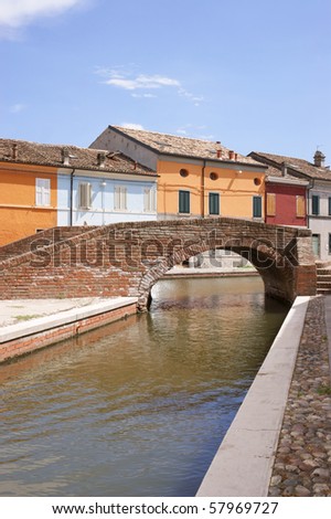 Stone arch bridge over a canal with colored houses behind